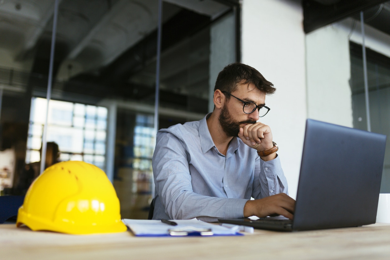 Architect working for a construction company working on his laptop at his desk.